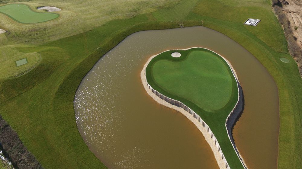 Atlanta Aerial view of a vibrant green synthetic grass island in a natural pond on a golf course